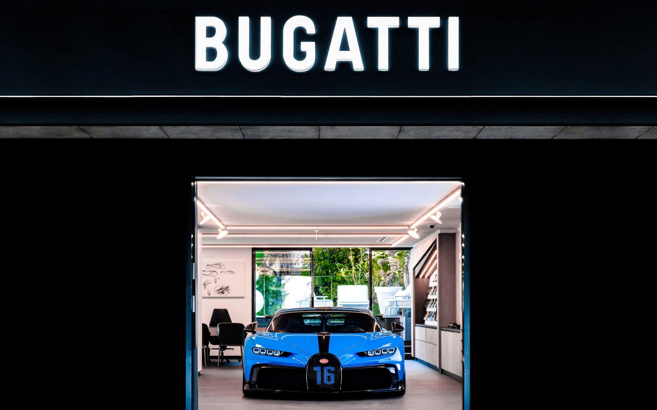 Bugatti Chiron coloured in Blue with a black stripe on bonnet stands in a dealership.